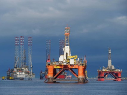 Several oil rigs are on the water under a dramatic cloudy sky, inverness, scotland, uk