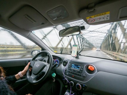 View from inside a car on a rainy day driving over a bridge with a phone for navigation, A1 A8