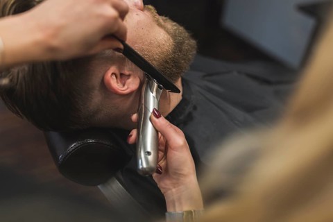 Anonymous woman trimming beard man