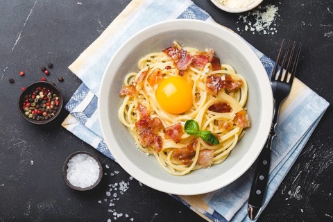 Traditional Italian pasta dish, spaghetti carbonara with yolk, parmesan cheese, bacon in plate on