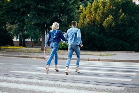 Back view of young happy couple running crosswalk in the street. Fun, walking, dating concept