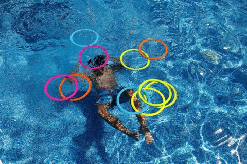 Boy playing with colourful rings in swimming pool, Province of Quebec, Canada, North America