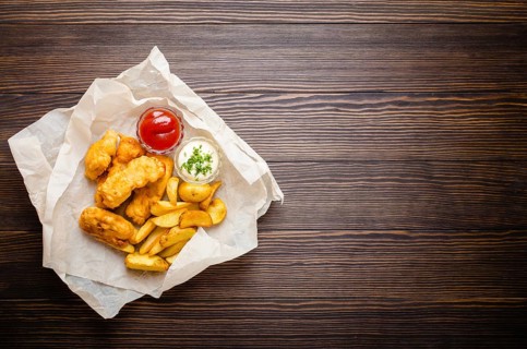 British traditional fast food fish and chips with assorted dips for choice, on paper, rustic wooden