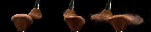 Make-up Brush spreading blush powder on black background