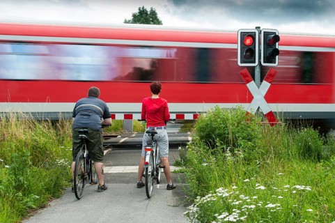 Man and woman standing with bicycles at a closed railway crossing