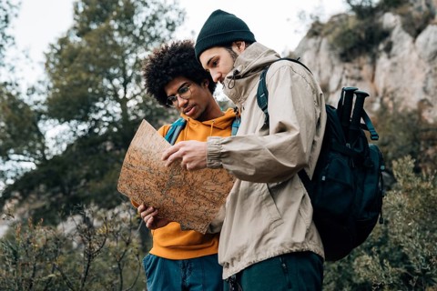 Low angle view hiker reading map while hiking nature