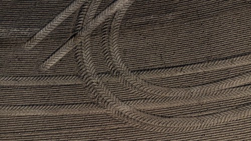 Tractor tyre tracks form an interesting pattern on a freshly cultivated field without vegetation,