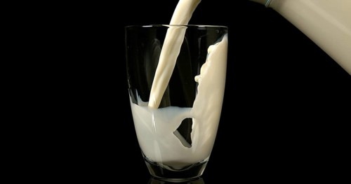 Milk being poured into Glass against black Background