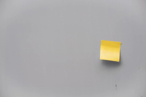 Yellow post-it note on a grey wall