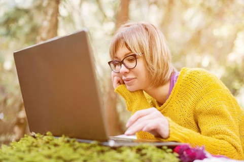 Toned image of a freelancer girl portrait in a yellow sweater and glasses looking thoughtfully at