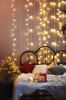 Tray with decorations and gift box placed on comfortable bed in cozy bedroom decorated for