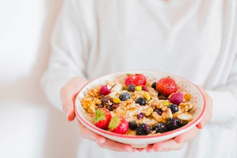 Crop person holding bowl oatmeal