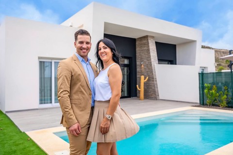 Portrait of a happy couple standing on the pool of their new luxury home