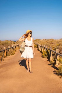 Vertical photo of a woman walking with a beach bag along a marked trail in Cabo de Gata, Spain,