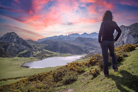 A young woman looking at the beautiful Covadonga lake in Asturias in a beautiful spring sunset,
