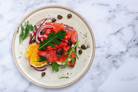 Sandwich with freshly smoked salmon, on black bread, with cottage cheese, with herbs and red