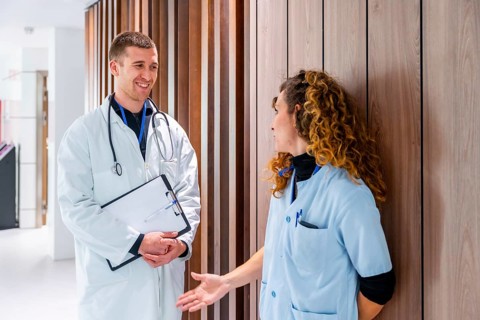Team work of a female nurse and doctor talking in the corridor of an hospital