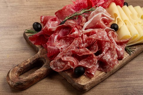 Assorted meat, appetizer, prosciutto, salami and ham, with maasdam cheese and olives, on a wooden