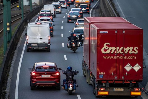 Motorcyclists overtake the partly stationary, partly slow-moving traffic in the middle of the
