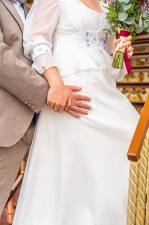 A bride and groom are standing on a staircase, the bride holding a bouquet of flowers. Scene is