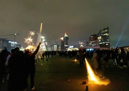Person launches firework rocket from his hand, New Year's Eve 2025 on the Elbe promenade in