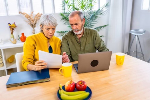Paperwork in the living room where a senior couple with laptop for finance planning with retirement