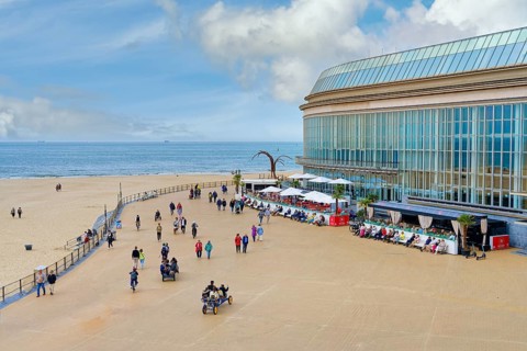 People walking and resting on Ostende promenade near the Kuursal casino, Ostende, West Flanders,
