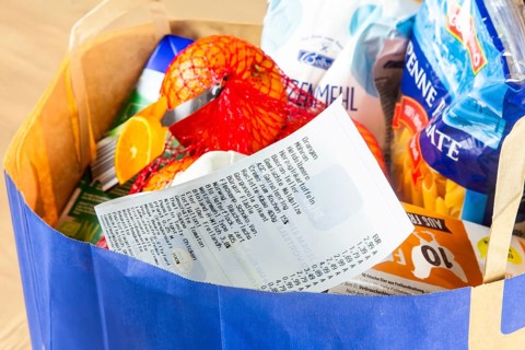 Symbolic image of food prices: Shopping bag full of groceries with a receipt