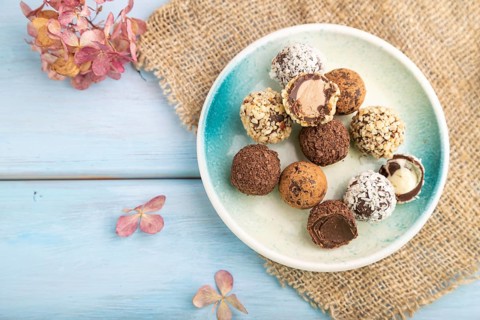 Chocolate truffle candies with cup of coffee on a blue wooden background and linen textile. top
