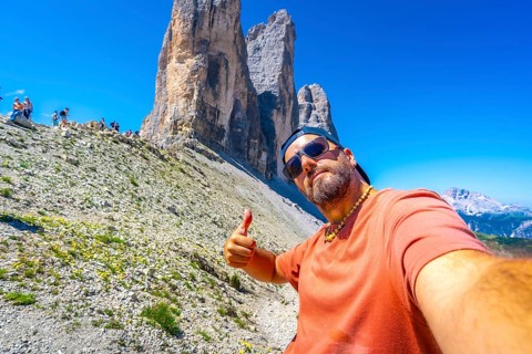 Tourist taking a selfie and making thumbs up gesture while hiking in the tre cime di lavaredo,