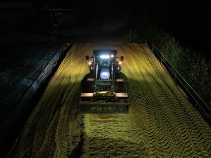 Tractor at night working on a silo filled with crop, maize harvest, Dachtel, Black Forest, Germany,