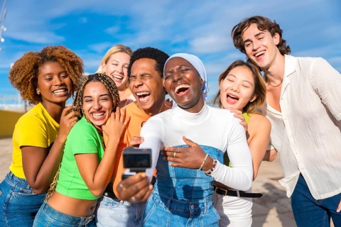 Muslim african woman taking a selfie while laughing with multi-ethnic and transgender friends
