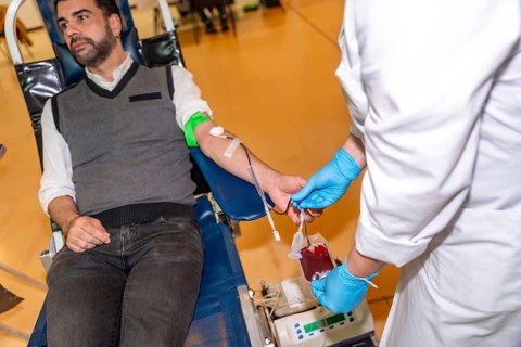 Unrecognizable female doctor collecting blood from a male donor into a bag