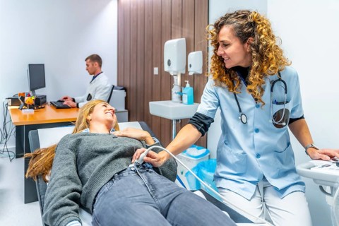 Nurse performing an ultrasound to the belly of a woman lying on stretcher in the hospital