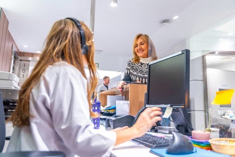 Receptionist of an hospital attending a mature woman standing in front the desk