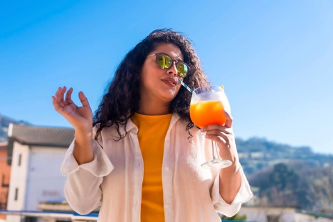 Cool woman sucking a cocktail with straw in a rooftop during a summer party