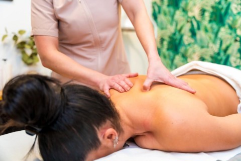 Close-up cropped photo of an unrecognizable masseur giving a back massage to a woman lying on