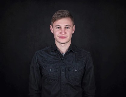 Portrait of a carefree young man against a black wall background looking to camera. Relaxed male