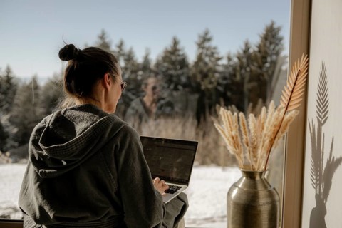 Woman in bathrobe sitting with a laptop on her lap in a garden
