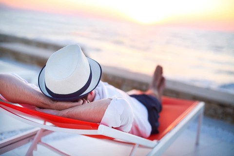 Young man relaxing on the beach back view. Summer vacation. Relax concept