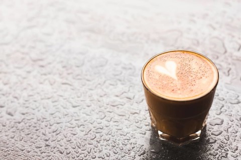 Hot latte with heart shape glass water drop surface