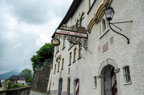 A traditional pub sign on a white wall of a European building on a cloudy day, Salzburg, Austria,