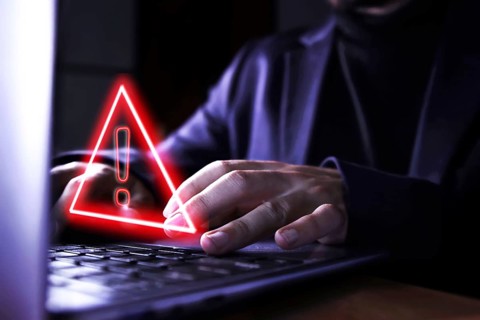 Hands of a businessman using the computer on fraudulent pages. Caution symbol of danger of hackers