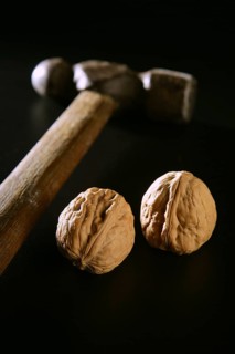 Two walnuts and old aged hammer over black background
