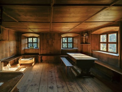 Farmhouse parlour with a small house altar in the dining corner and a baby cot, open-air museum