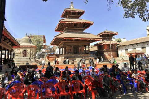 Group of people sitting on plastic chairs in front of a traditional temple, Kathmandu Valley,