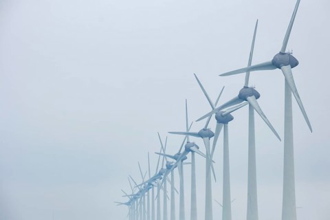 Wind turbines in a row on the coast in the mist and fog