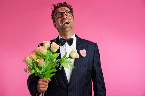 Nerd man with lipstick marks on face in Valentines Day and flowers