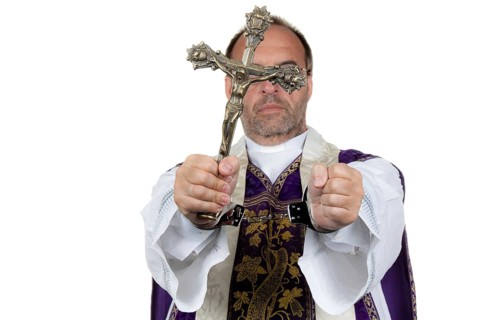 A Catholic priest with handcuffs as a symbol of child abuse. Austria