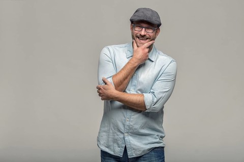 Thoughtful attractive middle-aged man with his finger to his mouth standing looking towards the